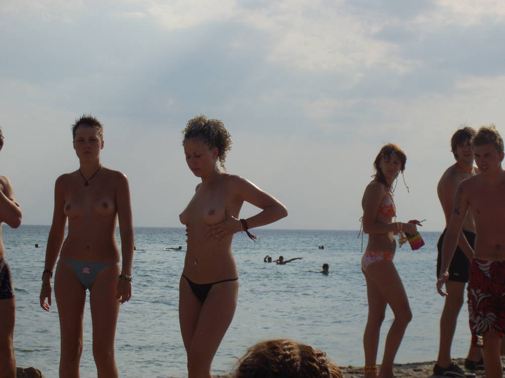 Couple of cute topless girls expose their beauty on sea shore