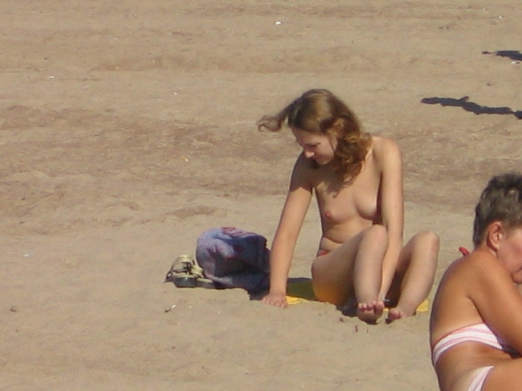 Sensual attractive topless babe with small tits exposed on the beach