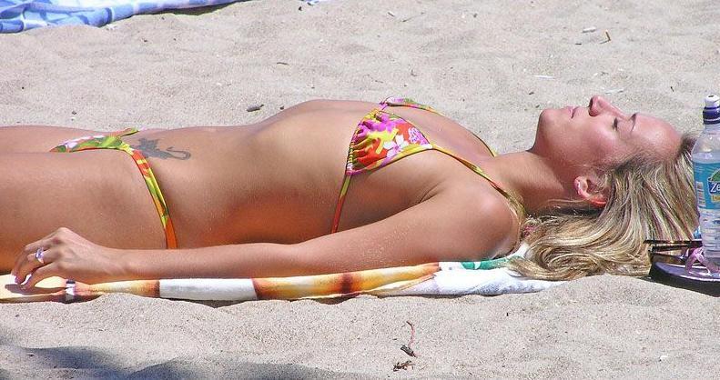 Tattooed sexy babe tanning on the warm beaches