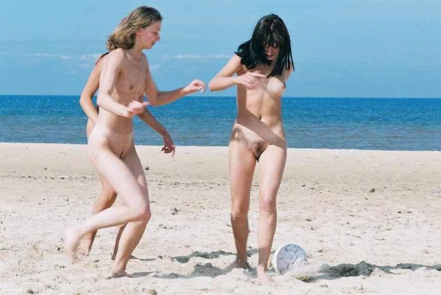 Attractive nude girls playing soccer in the sand
